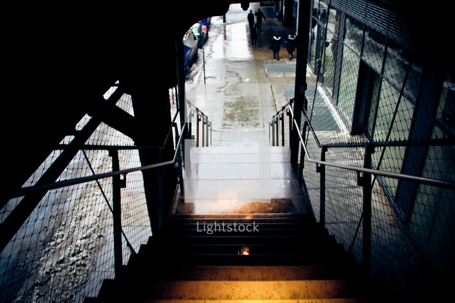 dark stairway leading to a wet sidewalk 