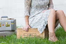 young woman sitting next to vintage luggage 