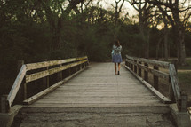 woman walking across a wooden footbridge 