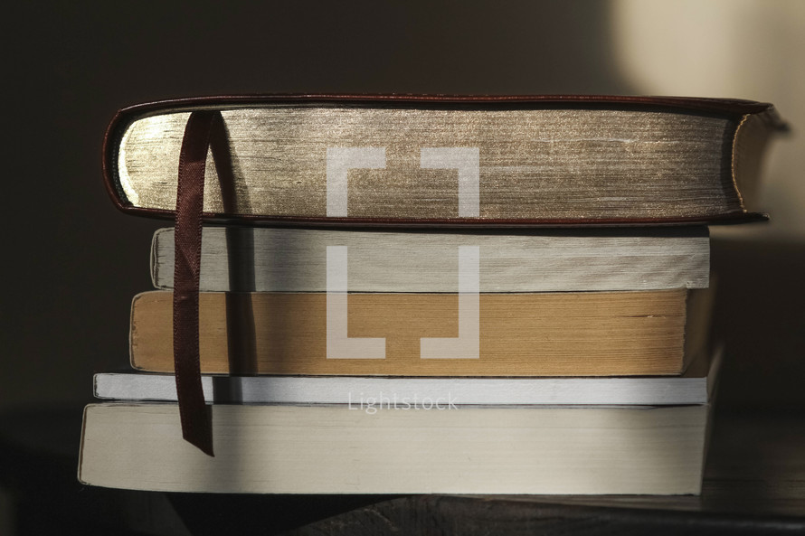bible on top of stacked books on a table 
