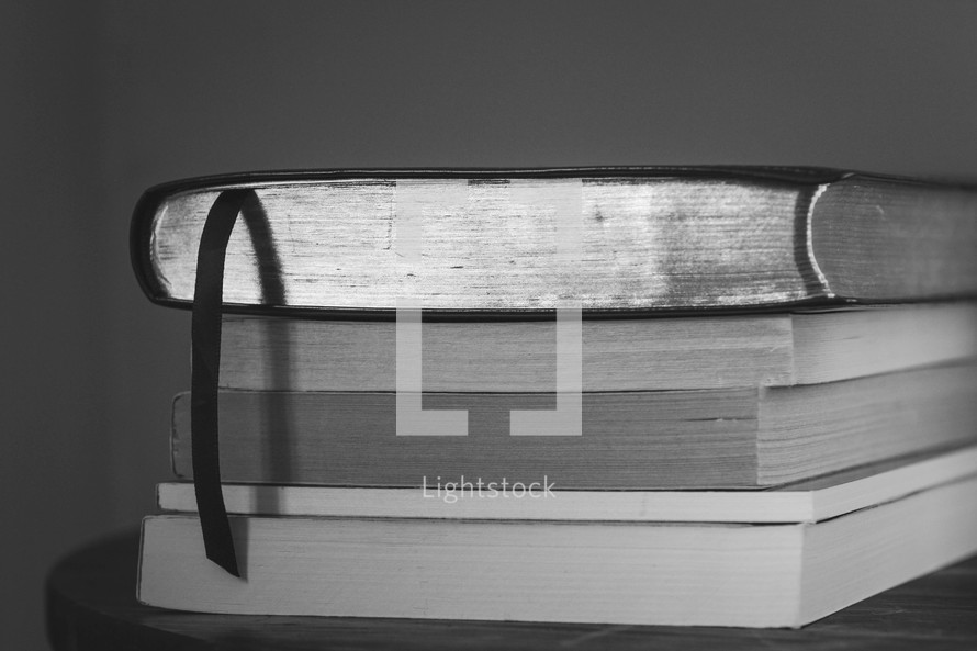 a Bible on top of stacked books on a table 