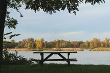 picnic bench by a lake in a park in fall 