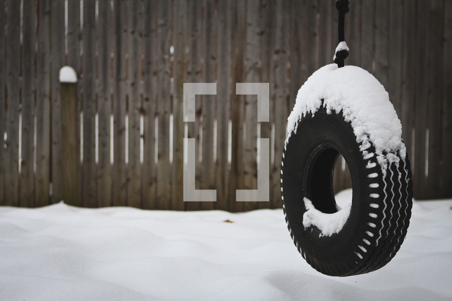 A tire swing in the snow.