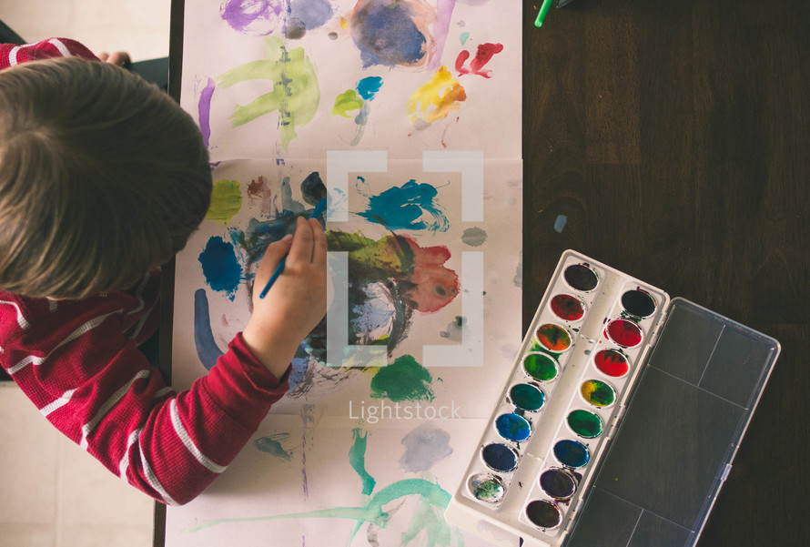a boy child painting with watercolors 
