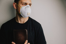 man in a N95 mask holding a Bible 
