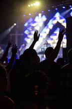 silhouettes of raised hands at a worship service 
