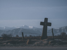 cross grave marker with frost and snow capped mountains in the background 
