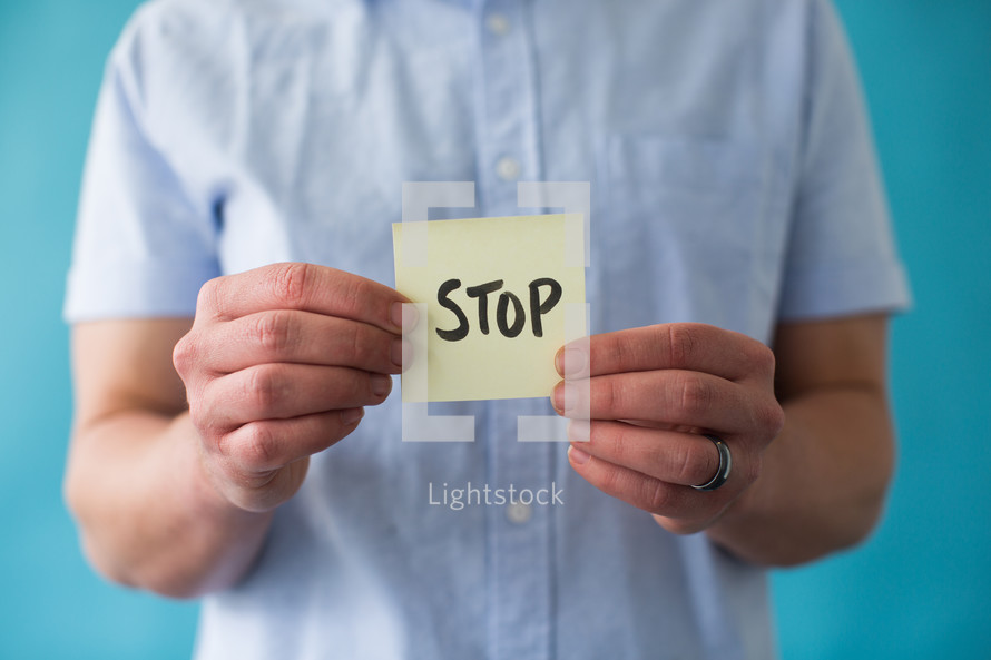man holding a piece of paper with word stop