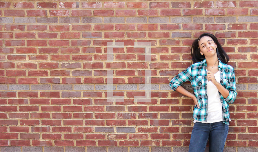 a girl standing in front of a brick wall 