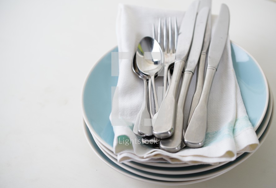 silverware and napkins on stacked plates 