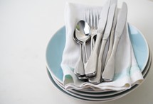 silverware and napkins on stacked plates 
