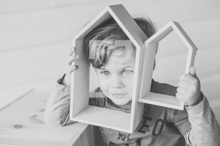 child playing with wooden house shaped blocks 