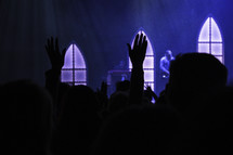 silhouettes of raised hands during a worship service 