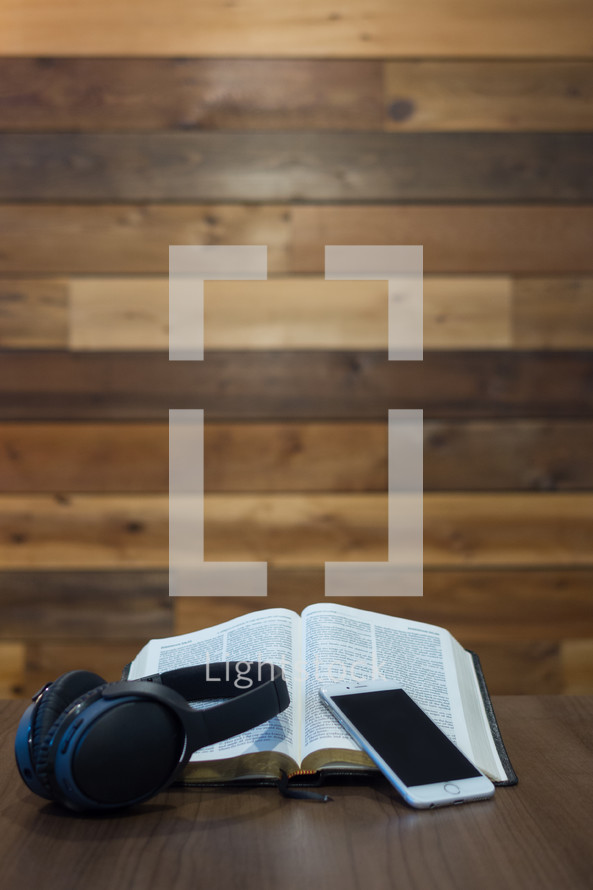 open Bible, headphones, and iPhone on a table 