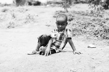 a little boy sitting on the ground 