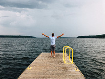 a man on a dock with arms outstretched
