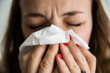 woman blowing her nose with a tissue 