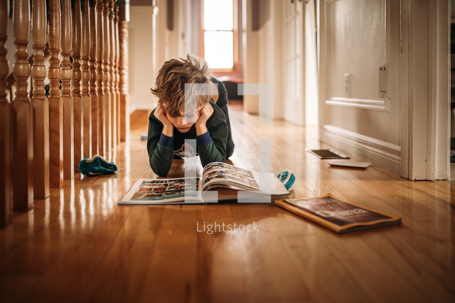 a child reading a book on the floor 