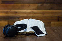 open Bible, headphones, and cellphone on a table 