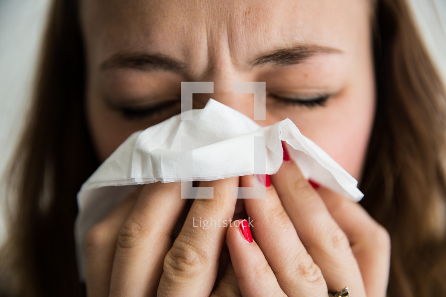 woman blowing her nose with a tissue 