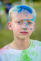 a boy with a colorful face after a color run 