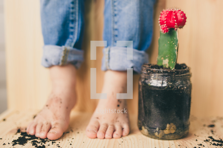 a boy with dirty feet and a mason jar with a cactus 