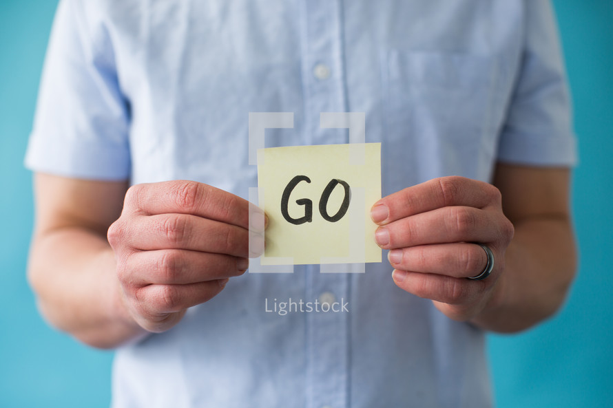 man holding a piece of paper with word go