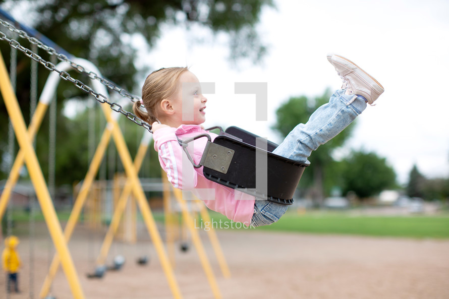 Little girl swinging high at the park 