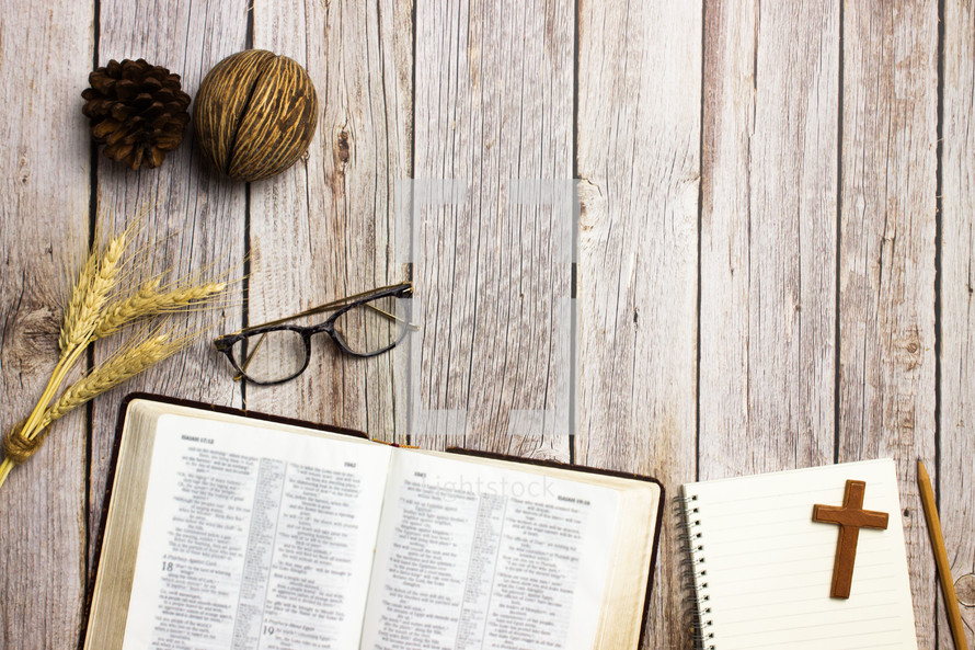 open Bible, notebook, and reading glasses on a wood background  