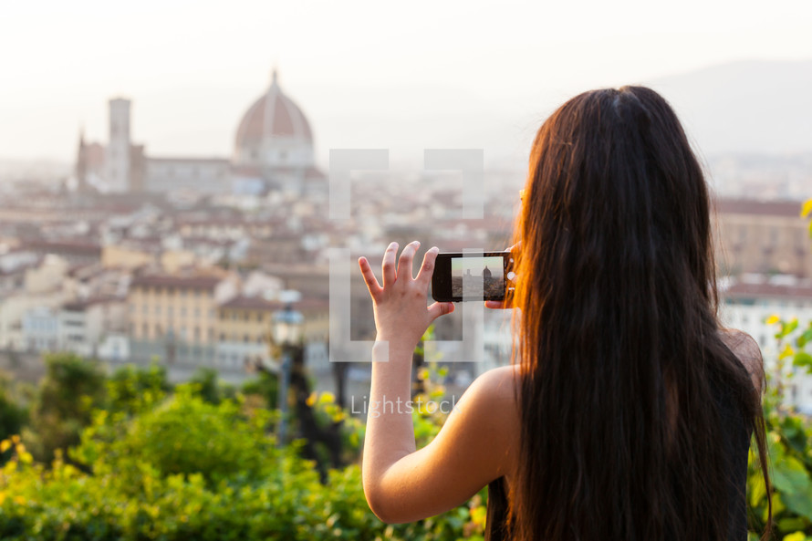 Teen at sunset in Florence takes a picture at the panorama with the smartphone