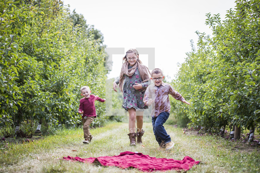 siblings running in an apple orchard 
