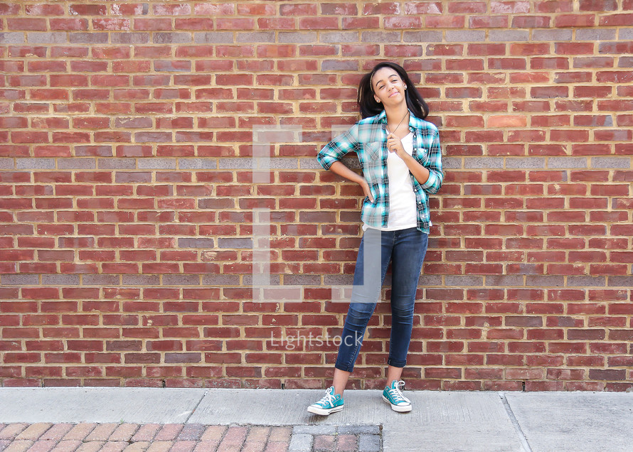 girl standing in front of a brick wall 