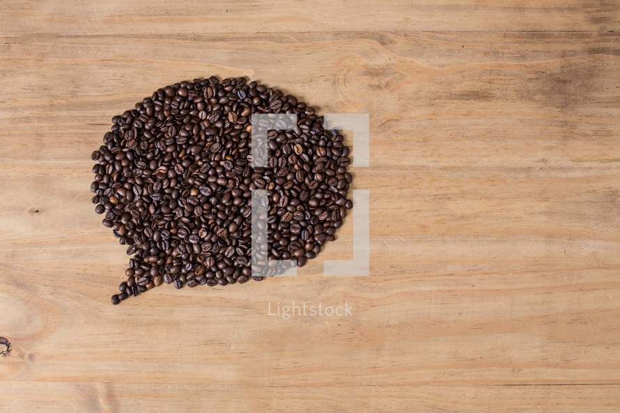 Coffee beans in a balloon formation on a wood table.
