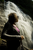 woman looking up at a waterfall