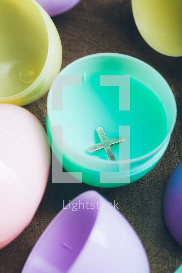 Silver cross inside a plastic Easter egg.