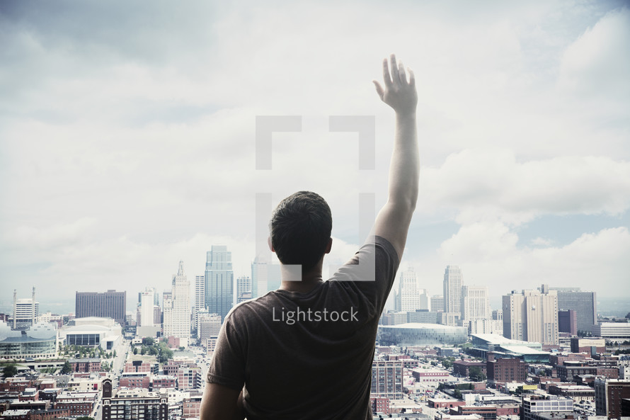 man standing in front of a city with hand raises 