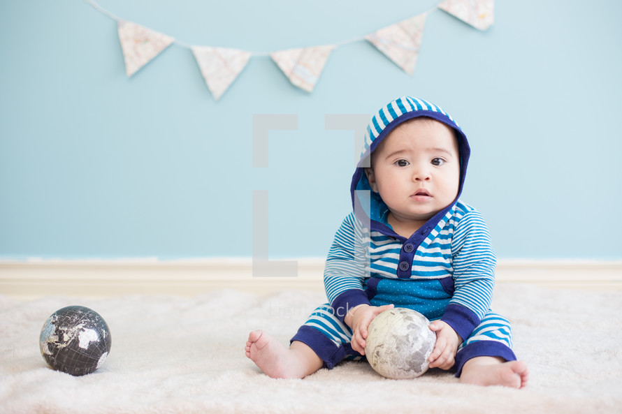 infant boy holding a globe ball 