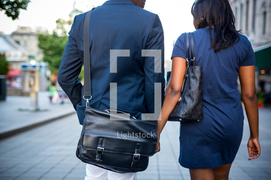 an African American couple walking down a sidewalk holding hands 