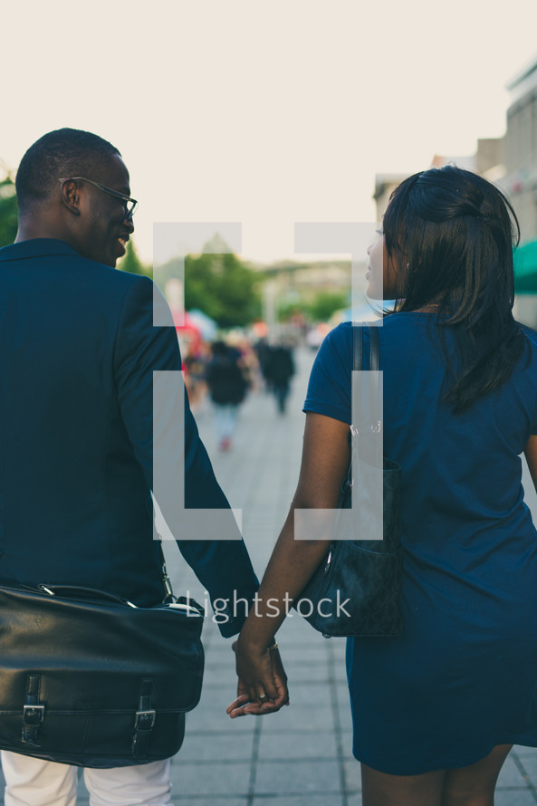 an African American couple walking down a sidewalk holding hands 
