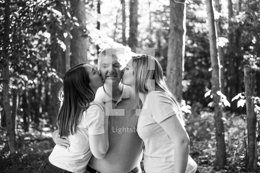 daughters kissing dad on the cheeks 