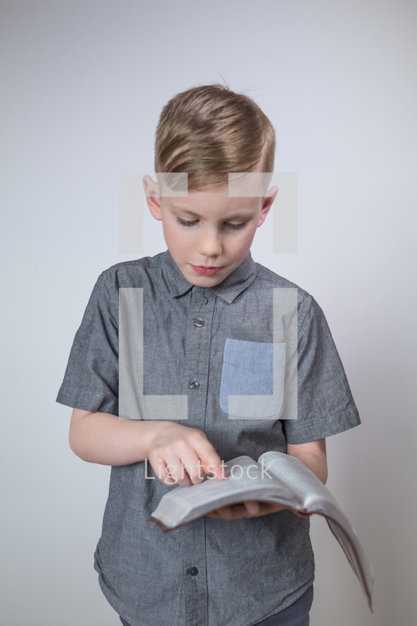 boy child standing reading a Bible 