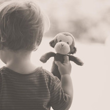 toddler boy carrying a toy monkey 