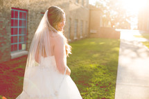 a bride walking outdoors under bright sunlight 