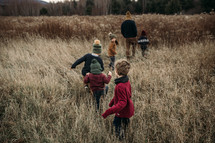 children running through a field of tall brown grass 