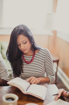 young woman reading a Bible at a table during a Bible study 