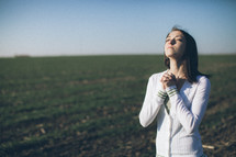 woman with her head lifted in prayer in a field