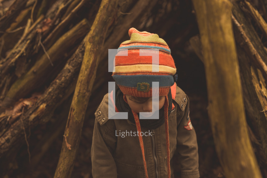 a boy child outdoors near logs