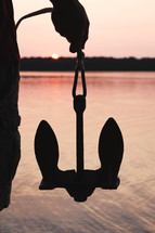 a man holding an anchor at sunset 