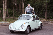 a man sitting on vintage Volkswagen Beetle 