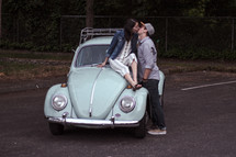a couple kissing on a vintage Volkswagen Beetle 